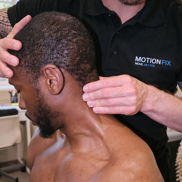 Chiropractor supporting a patient's neck during treatment at MotionFix